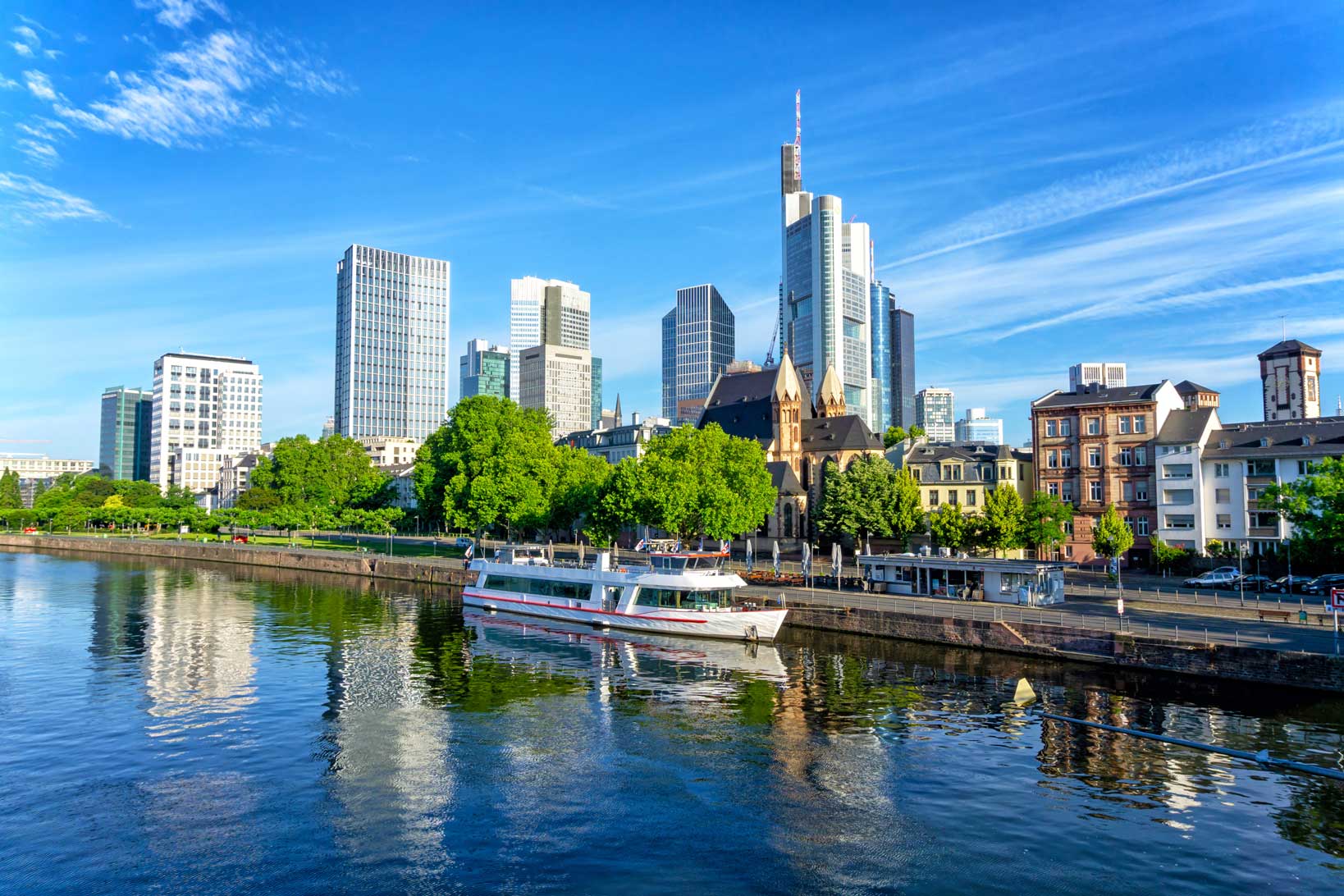 Frankfurt skyline viewed from the River Main with office towers, riverside buildings and a passenger boat.